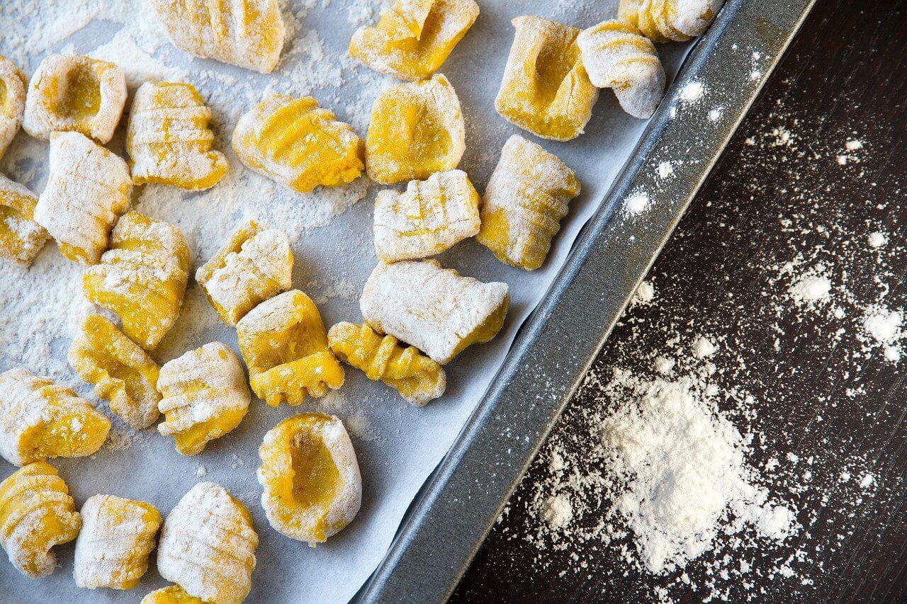 Homemade gnocchi on a tray with flour
