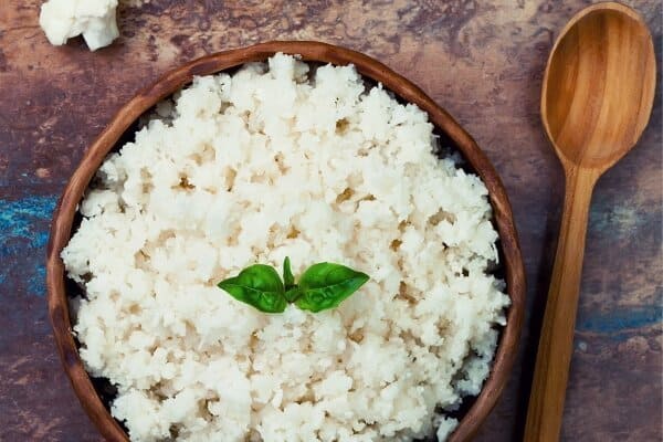 cauliflower rice in a brown bowl with spoon