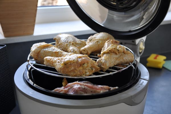 stacked chicken drumsticks on a rack in a basket style air fryer