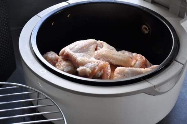 stacked chicken wings in a basket style air fryer