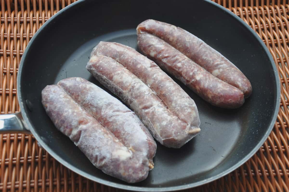 Frozen sausages in frying pan