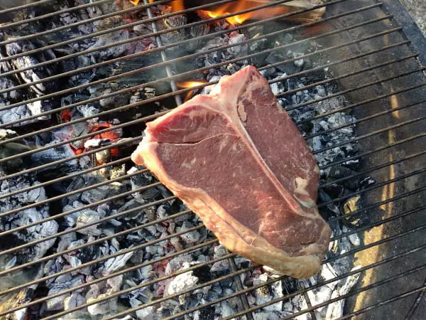 grilling steak on open fire